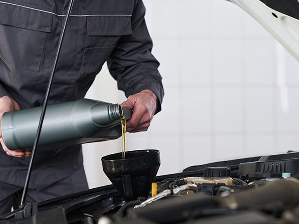 technician pouring oil into engine